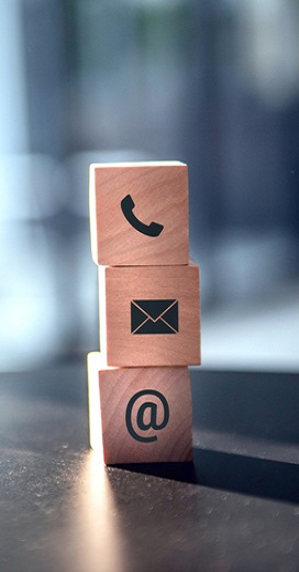 Wooden blocks stacked on top of each other. Bottom one with an @ symbol, middle with a rectangle, and top one with a phone.
